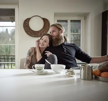 Junges Pärchen sitzt an einem Esstisch und umarmt sich.