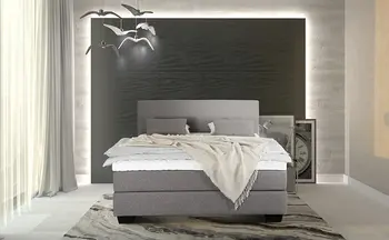 Graues Boxspringbett in modernem Schlafzimmer mit stilvoller Wandbeleuchtung und dekorativen Elementen, umgeben von hellen Vorhängen und minimalistischer Einrichtung.