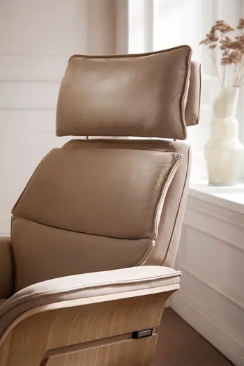Beiger Design Relaxsessel, bei dem das Kopfteil in der Höhe verstellt ist.