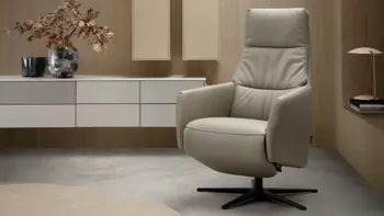 Moderner Designer Sessel mit beigem Leder, vor einer modernen Wohnwand in beige.