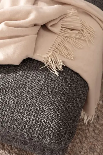 Ecke eines grauen Sofas in Nahansicht.