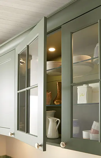 Küchenoberschrank in grünem Holz mit Glaseinsätzen.