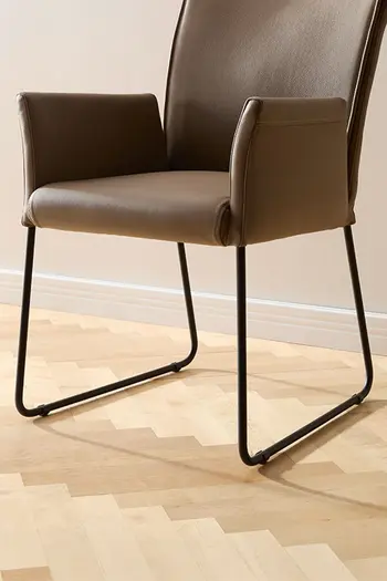 Esszimmerstuhl in dunkelbraunem Stoff mit schwarzem Kufengestell aus Metall.