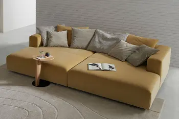 Gelbes Design Daybed mit vielen Kissen und einem kleinen hellen Beistelltisch.
