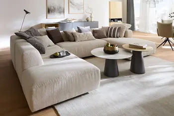 Elegantes Wohnzimmer mit großer Wohnlandschaft in beigem Stoff und zwei runden Couchtischen in Marmoroptik.