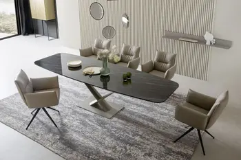 Großer Designer Esstisch mit schwarzer Keramik Tischplatte und silbernem Fuß in einem hellen Raum, fünf graue Leder - Armlehnstühle stehen um den Tisch.