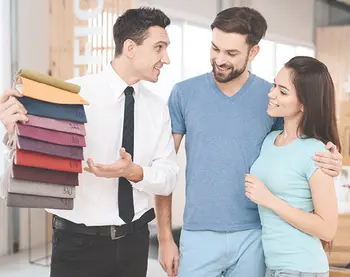 Paar betrachtet gemeinsam mit einem Berater auf einem Tablet Wohnlösungen in einer modernen Küche.