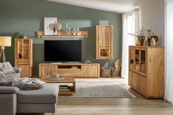 Wohnwand aus hellem Holz mit breitem Holzrahmen und vielen Glaseinsätzen in einem gemütlichen Wohnzimmer mit grüner Wand 