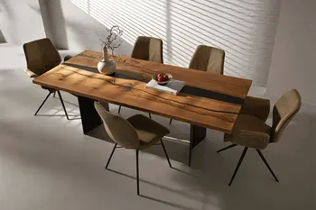 Großer design Massivholz Esstisch mit schwarzer Epoxidharz Füllung, um den mehrere grüne Design Schalenstühle stehen.