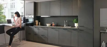 Anthrazitfarbene Kuechenzeile mit sitzender Frau und Barelement.