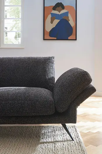 Nach unten geklappte Armlehne eines modernen Sofas in dunkelgrauem Stoffbezug.