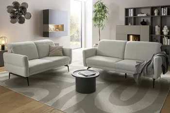 Zwei Sofa Garnituren in creme mit schwarzem Metallgestell in einem hellen modernen Raum.