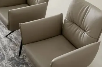 Beiger Armlehnstuhl, der mit Leder bezogen ist und an der Rückenlehne eine Quernaht hat.