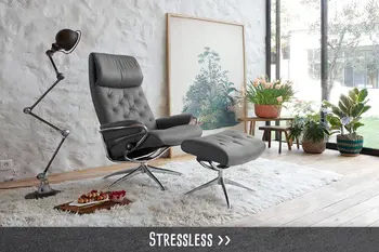 Moderner grauer Relaxsessel mit Hocker in stilvollem Wohnzimmer mit großen Fenstern und Pflanzen