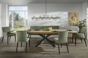 Großer ausziehbarer Esstisch aus Massivholz mit schwarzem Gestell, um den mehrerer Stühle und eine Sitzbank mit grünem Stoff stehen.