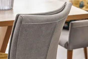 Rückenlehne eines grauen Esszimmerstuhls, der eine Naht in der Mitte der Rückelehne hat.