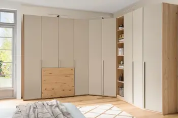 Großer Kleiderschrank, der in einer Ecke steht mit beigen Fronten und Holzakzenten.