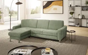 Grünes gemütliches Ecksofa in einem hellen Raum.