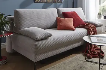 Graues Schlafsofa mit roten Kissen und roter Decke.