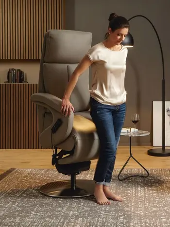 Hellbrauner Relaxsessel, aus dem eine Frau mithilfe der Aufstehhilfe aufgestanden ist.