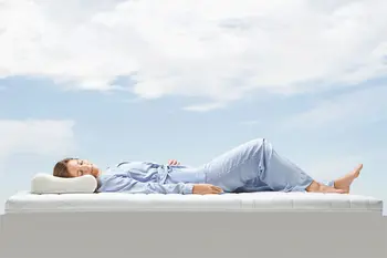 Schlafende Frau liegt auf einer Matratze unter freiem Himmer.