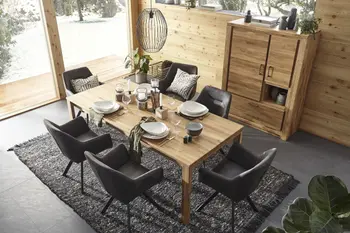 Großer Esstisch aus Holz in einem gemütlichen Esszimmer mit Tellern, Gläser gedeckt vor dem graue Schalenstühle mit schwarzen Beinen stehen.
