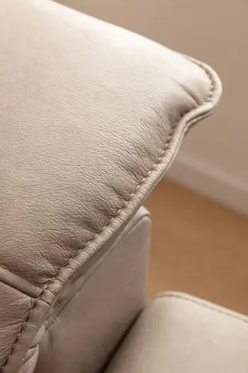 Nahaufnahme der Naht einer klappbaren Kopflehne eines grauen Ledersofas.