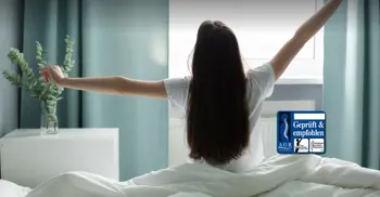 Frau streckt sich nach dem aufwachen im Bett.