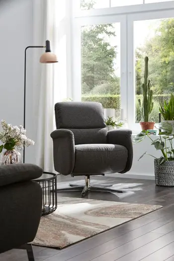 Grauer Sessel mit silbernem Sternfuß in einem hellen Raum.