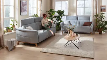 Wohnzimmer mit zwei Zweisitzersofas in hellblauem Stoffbezug und ovalem Couchtisch.