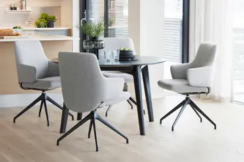 Essbereich mit Stressless Laurel Esszimmerstühlen in Clover Light Grey Stoffbezug und schwarzem Untergestell um einen runden, dunklen Esstisch. Der Raum ist hell und modern mit Blick auf die Terrasse.