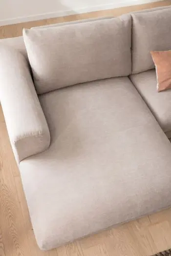 Graues Ecksofa mit abgerundeten Ecken und Longchair.