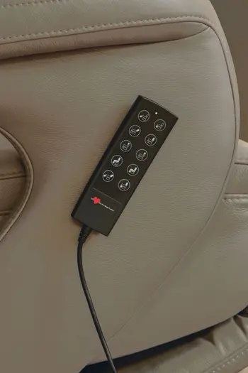 Seite eines hellbraunen Relaxsessels, an der die Fernbedienung zur Steuerung angebracht ist.