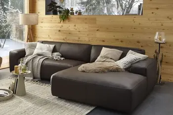 Ecksofa mit braunem Lederbezug in einem gemütlichen Wohnzimmer mit Holzwand.