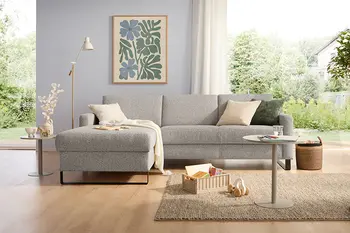 Beiges Ecksofa mit großen Rückenküssen und schwarzem Kufengestell.